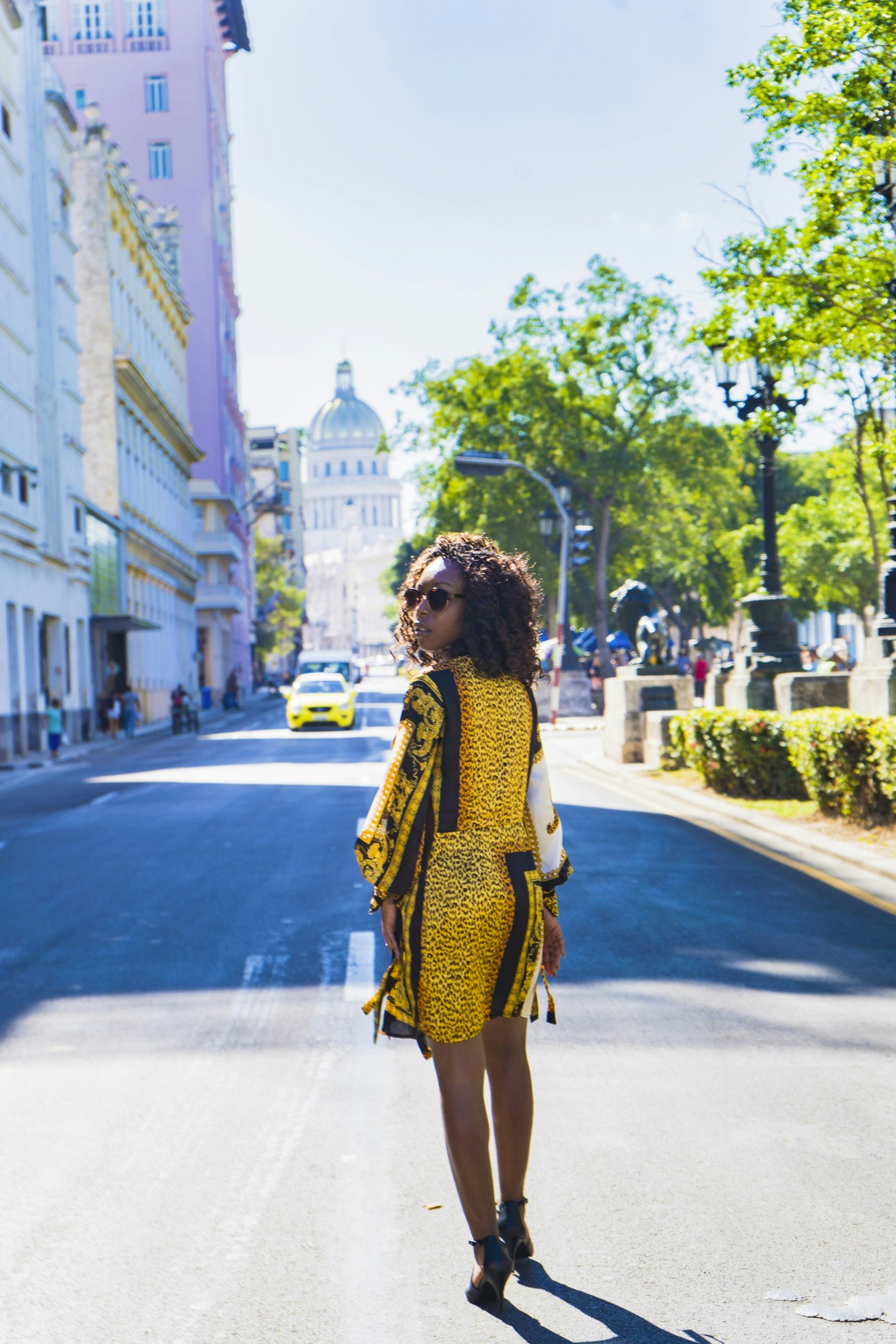 A black woman looks back as she walks down a street in Cuba